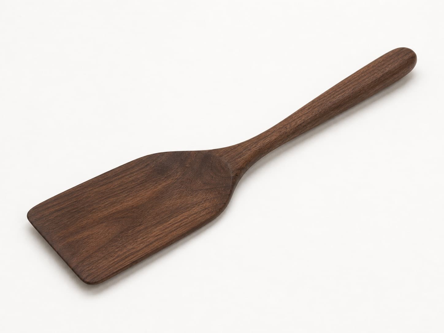 Flat wooden spatula turner with broad squared head shown in black walnut